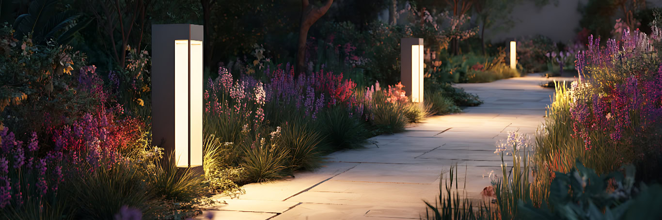 Beleuchteter Gartenweg mit blühenden Pflanzen bei Nacht.