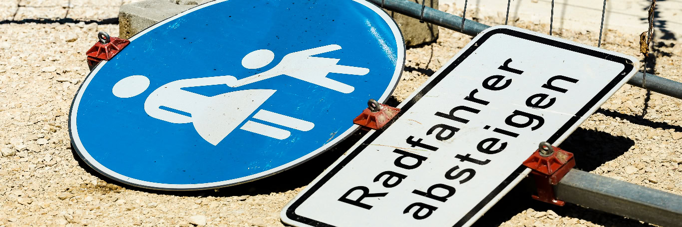 Umgestürzte Verkehrsschilder auf sandigem Untergrund.