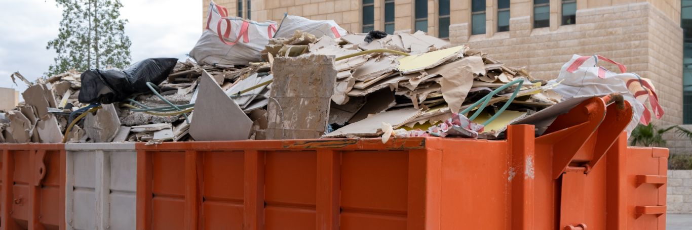 Bauschutt in großem orangefarbenem Container.