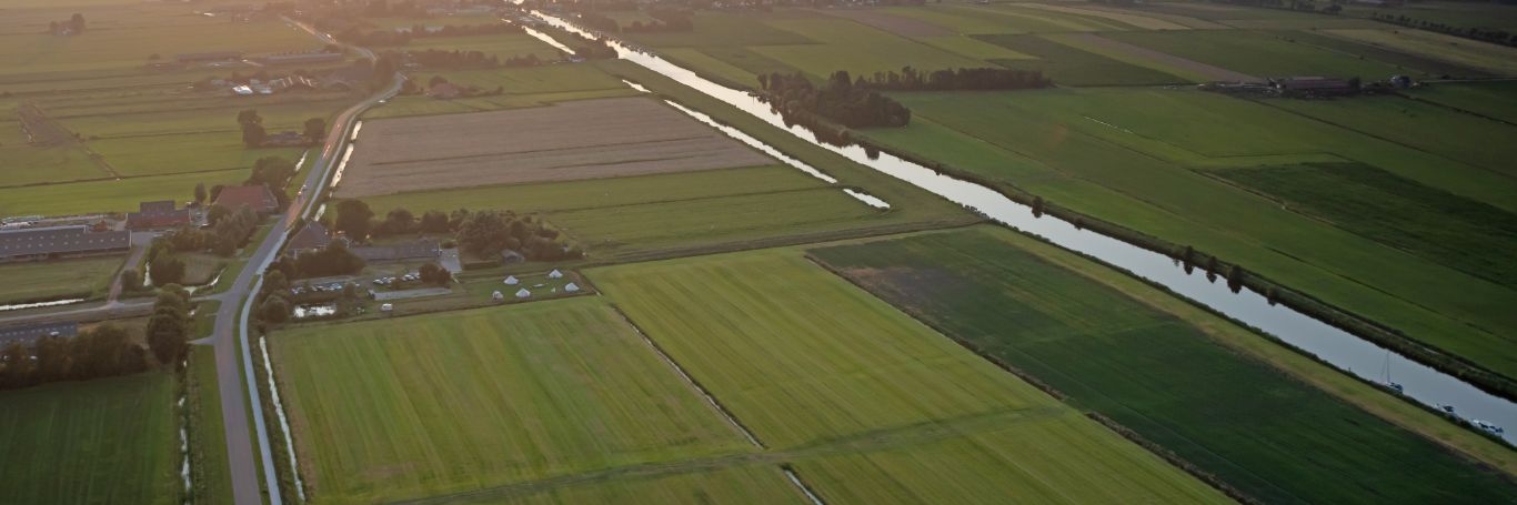 Luftaufnahme von Feldern, Fluss und Straßen bei Sonnenuntergang.